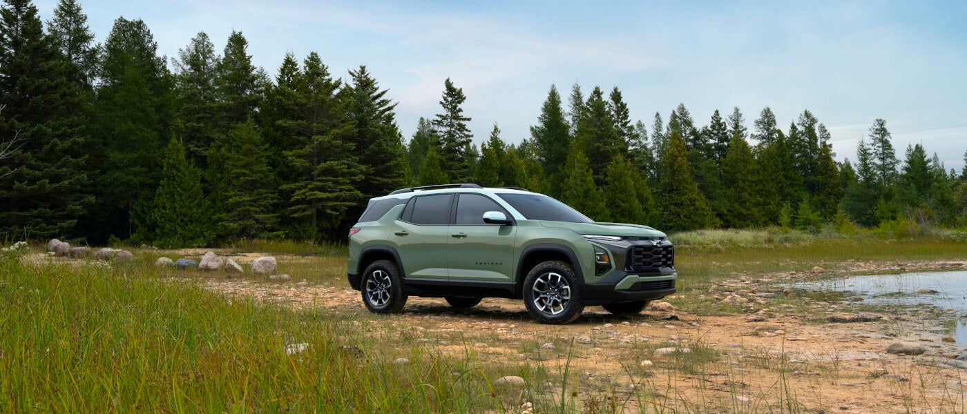 2026 Chevy Equinox parked on rocky shoreline with trees